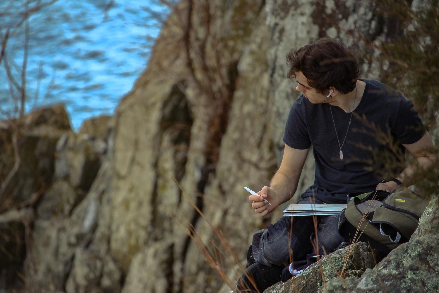 A man writing in a notebook outdoors