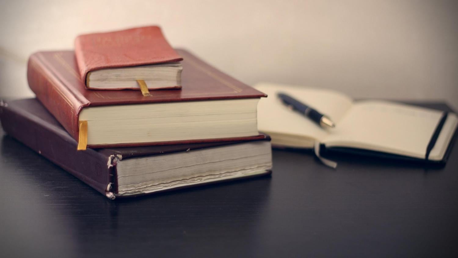 three books and a pen on a planner
