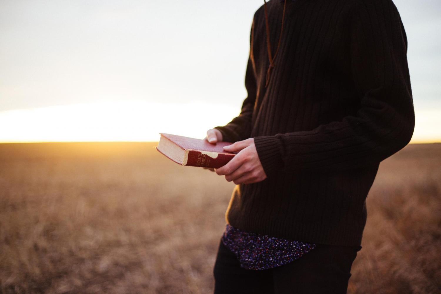 man holding book in field