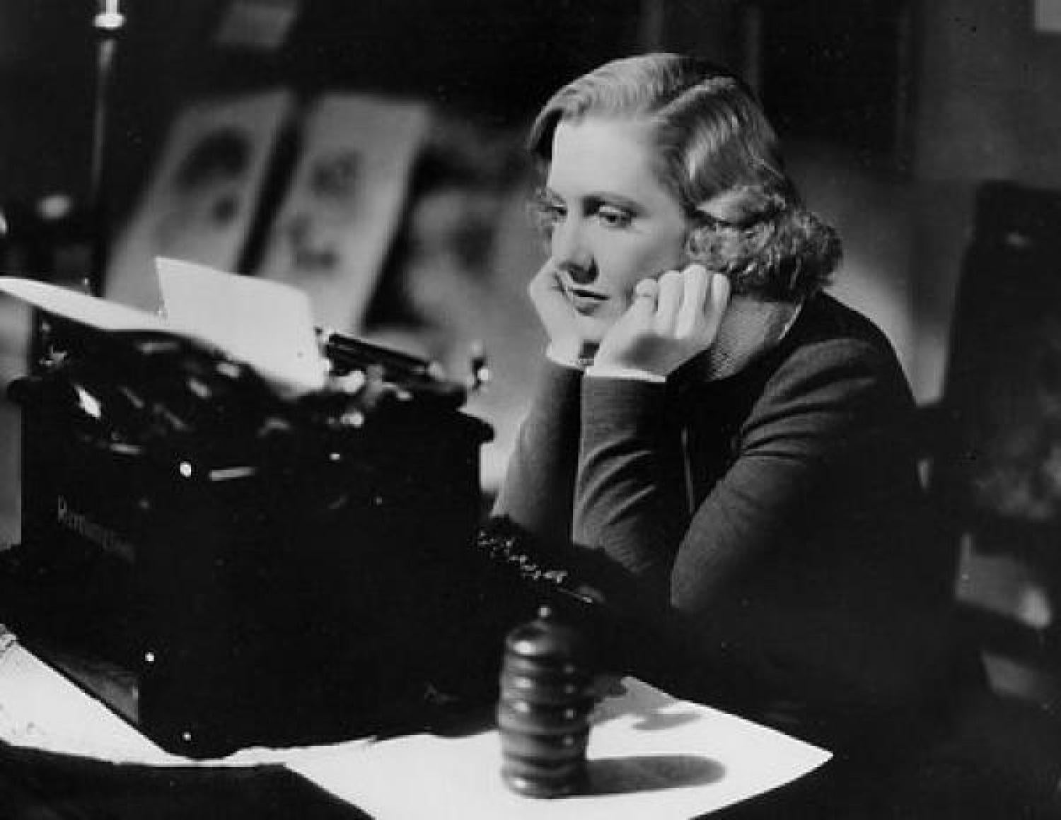 Woman at a desk with a typewriter looking frustrated