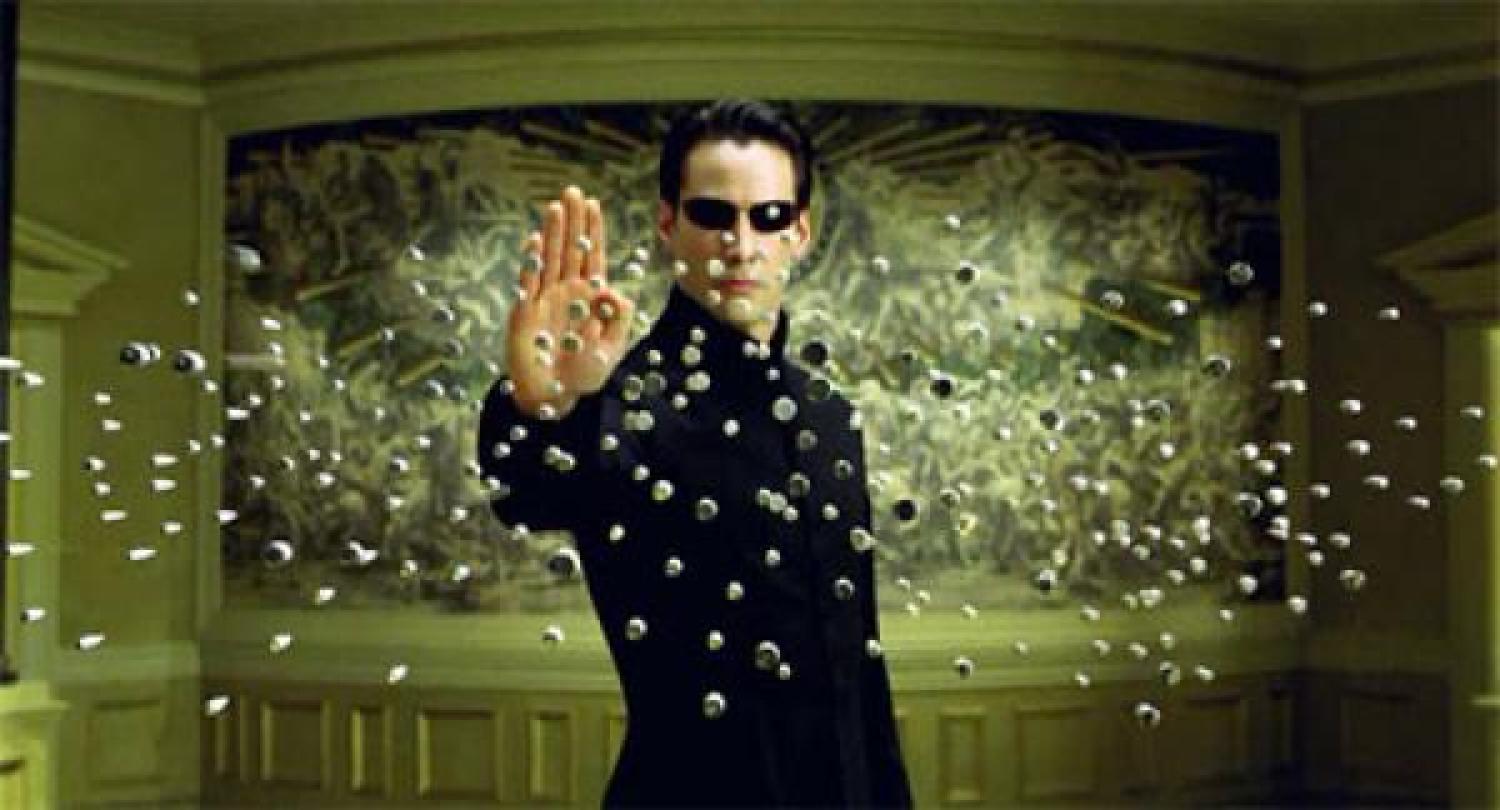 A man holding his hand out with bullets flying at him
