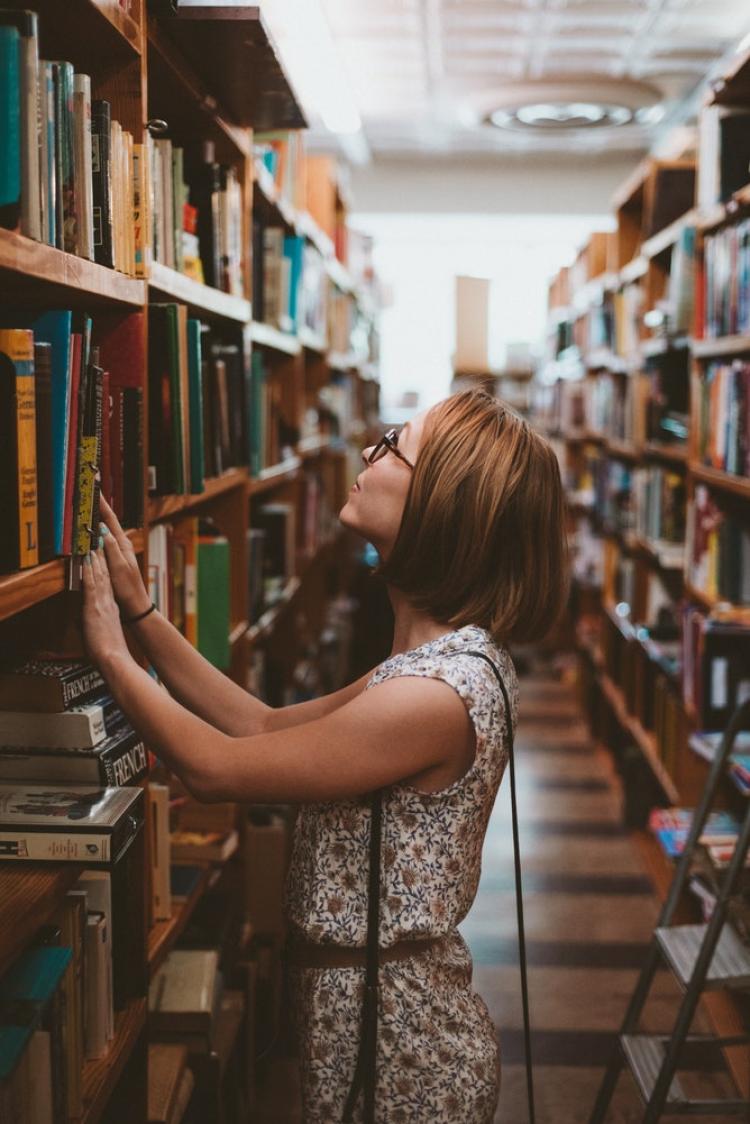 Woman picking a book from a bookshelf