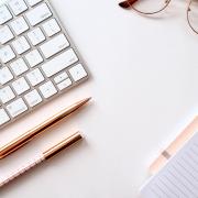 A white desk with a keyboard and a pair of glasses