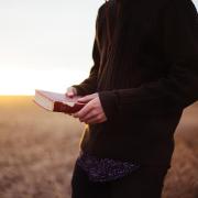 man holding book in field