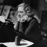 Woman at a desk with a typewriter looking frustrated