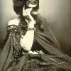 Photo of a woman in a dress covering her face with a mask