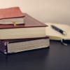 three books and a pen on a planner