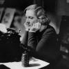 Woman at a desk with a typewriter looking frustrated