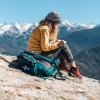 Woman writing in a notebook on top of a mountain