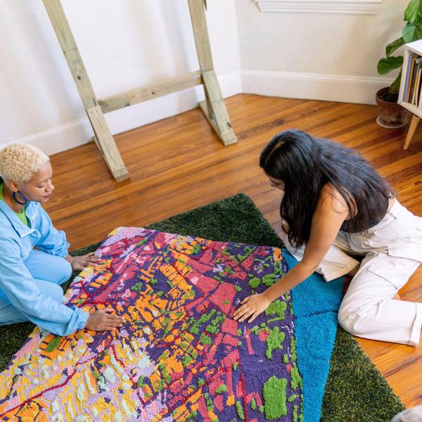 Sophie and her collaborator work on a tufted textile map