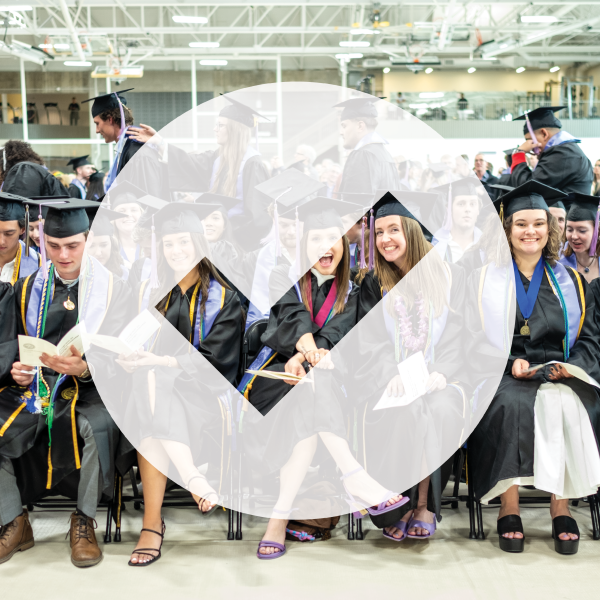 Checkmark graphic in front of a crowd of grads