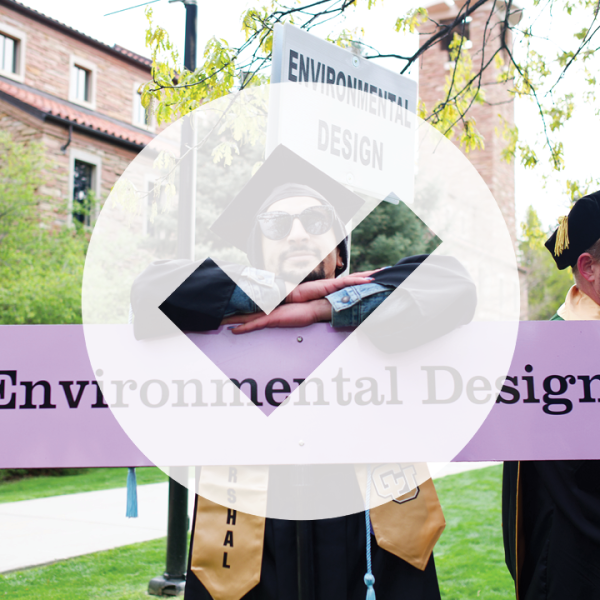Checkmark symbol in front of a staff member holding ENVD's graduation sign