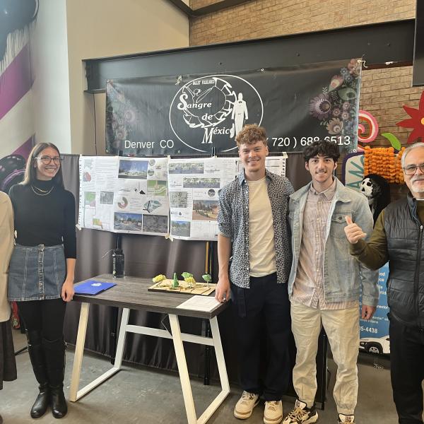 Students stand in front of their posters at the youth center