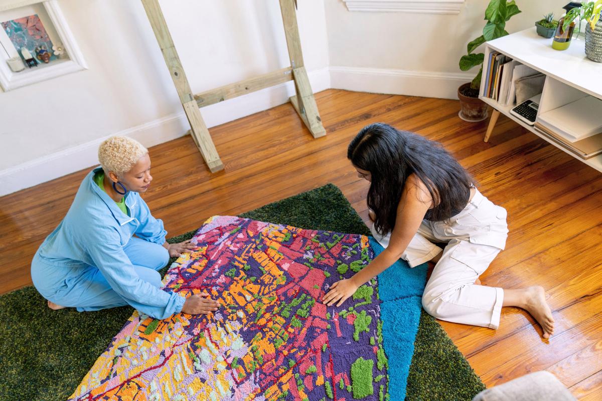 Sophie and her collaborator work on a tufted textile map