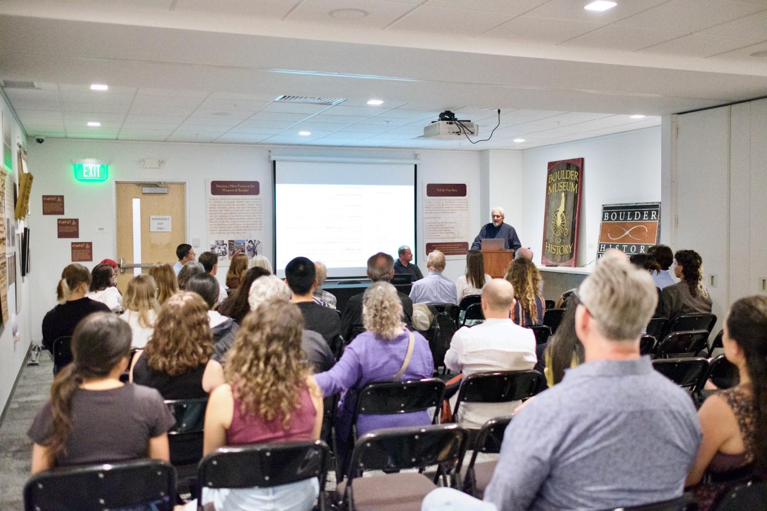 A room full of people sitting in chairs watching a presentation
