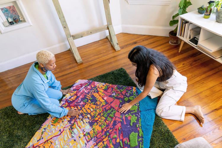 Sophie and her collaborator work on a tufted textile map