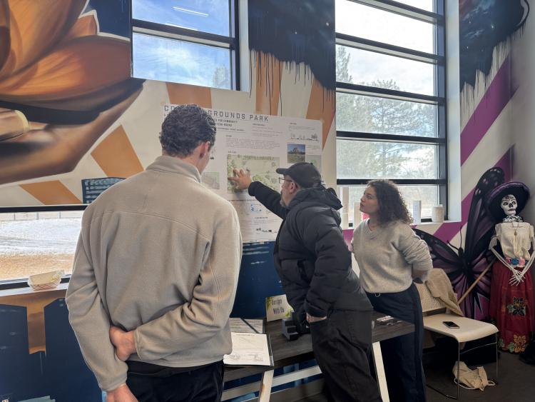 An audience gathers around a student's poster