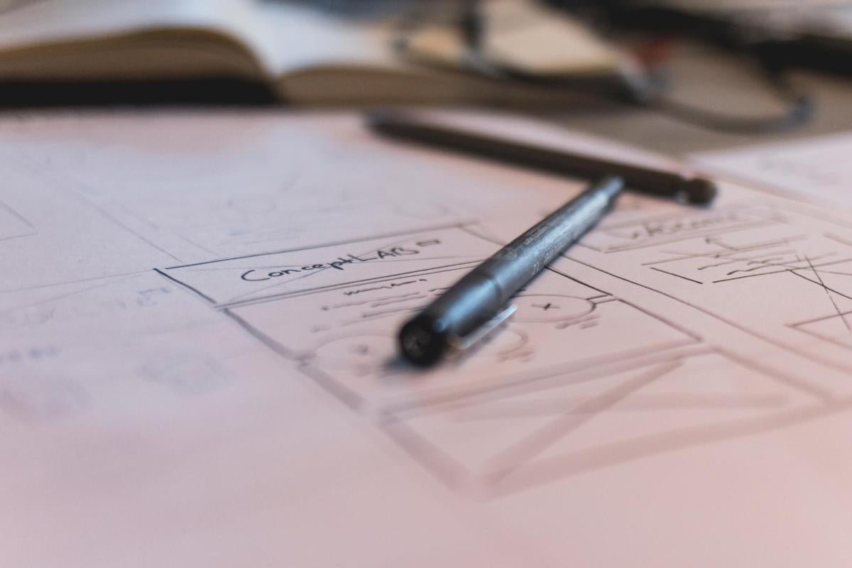 Image of a pen on paper with brainstorming images on the paper including the words "concept lab"