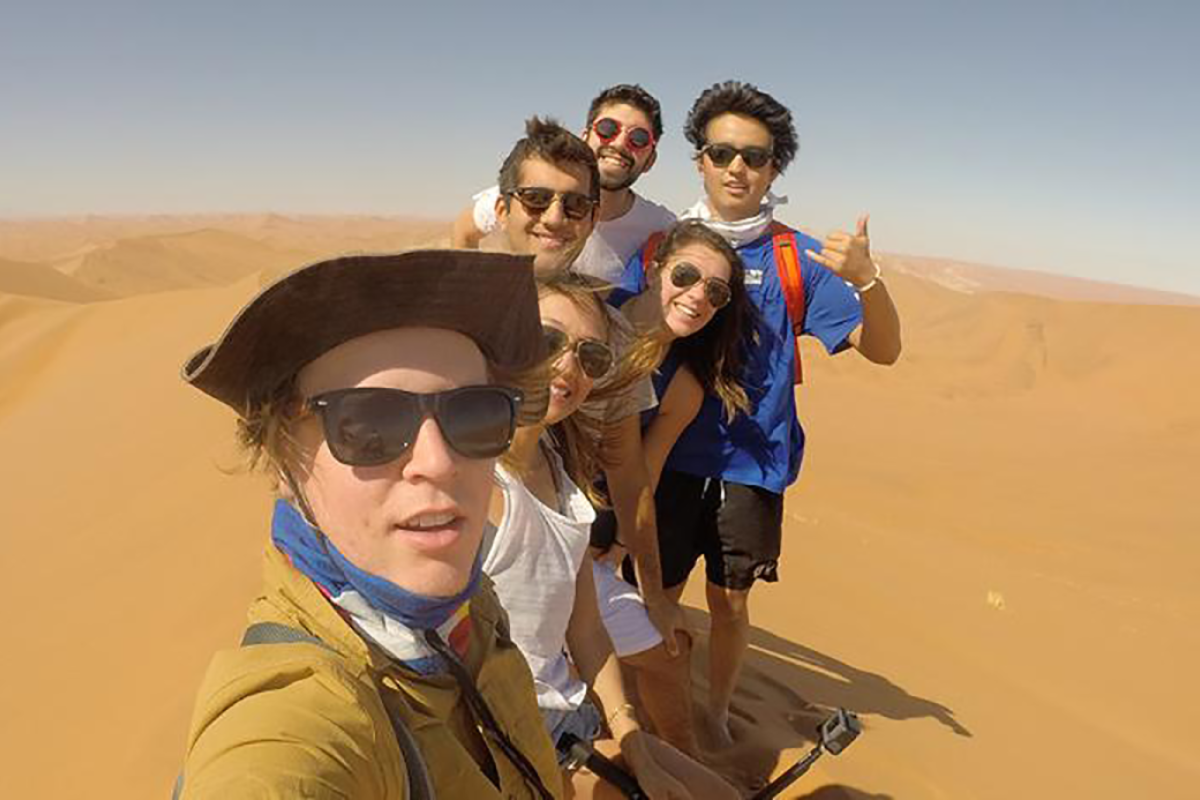 Students hiking a dune in Africa.