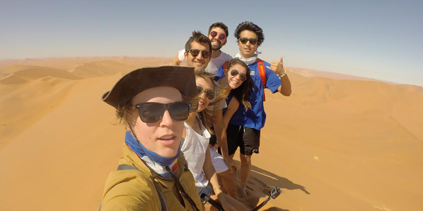 Students hiking a dune in Africa.