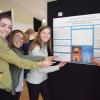 Four students pointing at a research poster