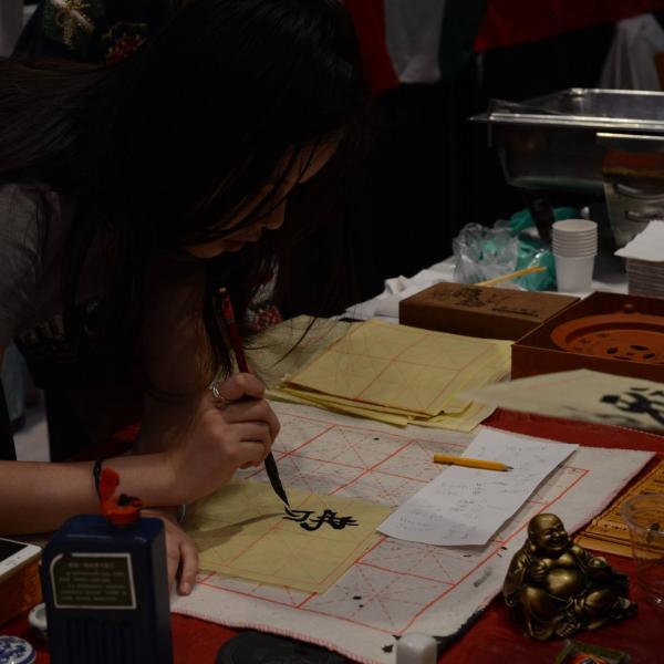 Student at Chinese booth doing Chinese manuscripts.