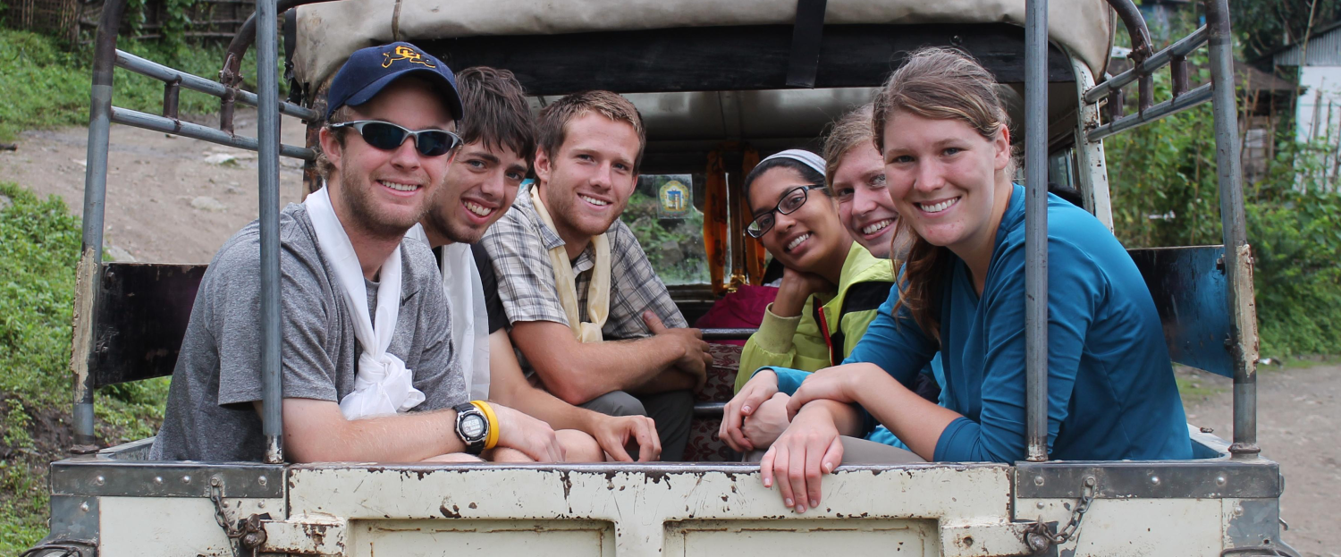 Students riding in the back of a truck as they participate in Engineers without Borders