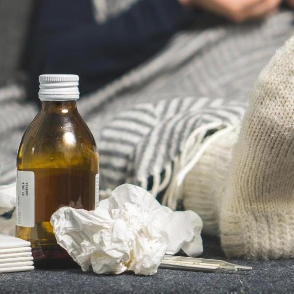 Sick person on couch with cold care supplies
