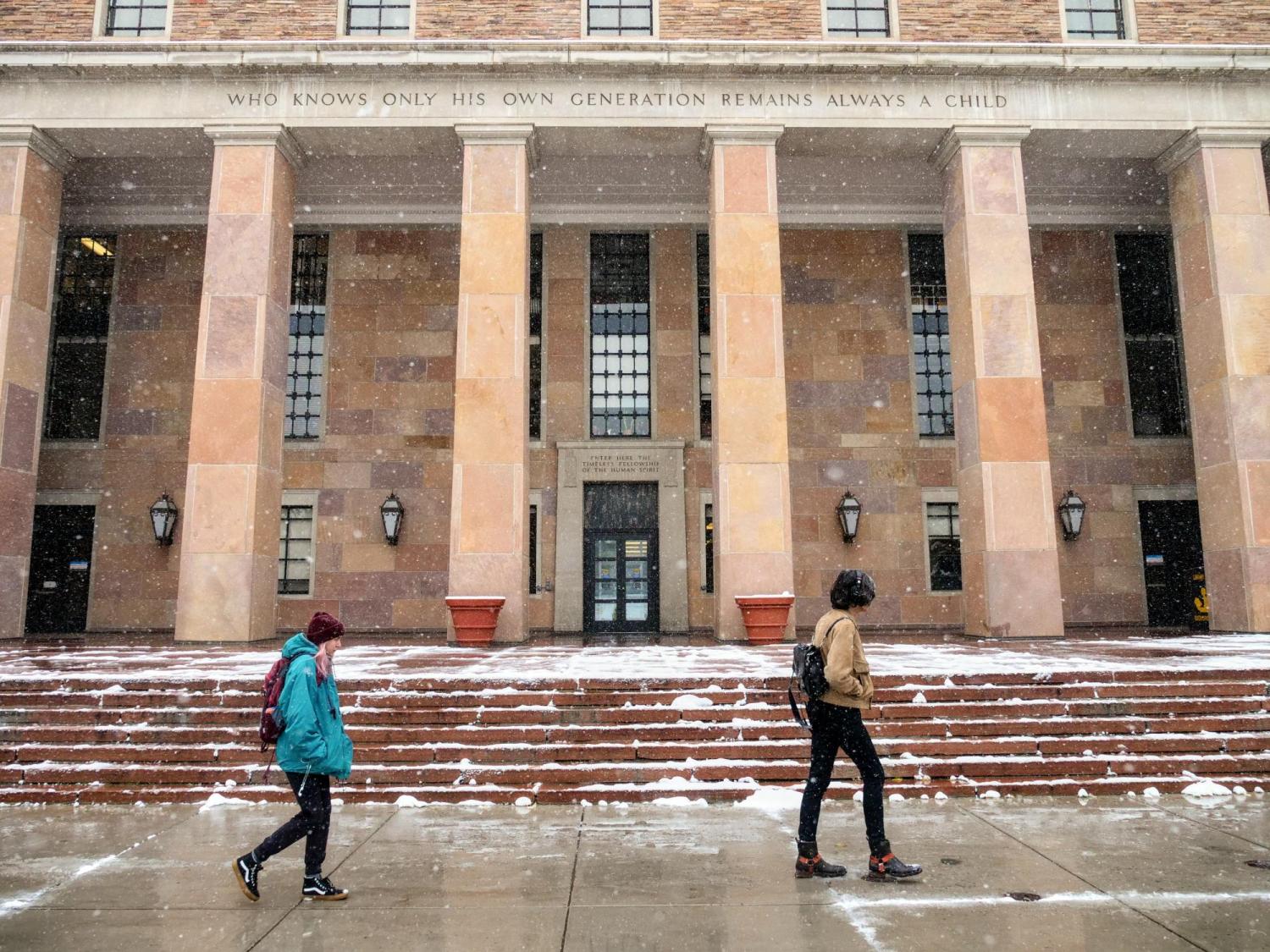 Students walking past snowy Norlin Library