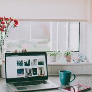 Coffee cup next to a laptop.