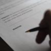Person holds pen above contract