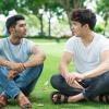 two students sitting in grass talking