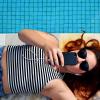 person lies by pool wearing ear buds