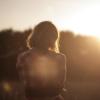 Woman sits on hill at sunset