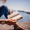 Person reading a book outdoors.