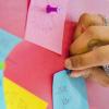 Person pins post-it note on wall