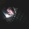 Person lying in bed in the dark looking at phone