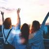 three friends with hands raised in the air