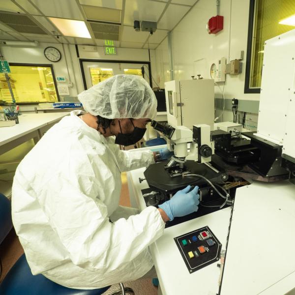 A person inside the clean room looking into a very large microscope