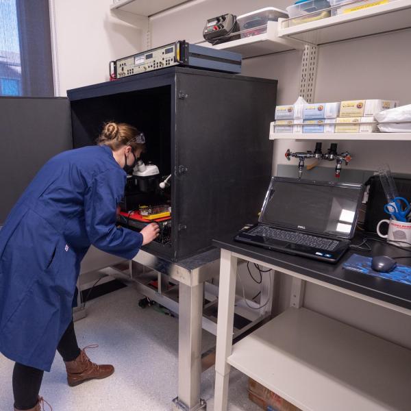 A person looking into a piece of lab equipment that looks like a microscope