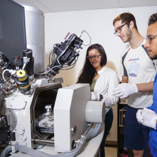 3 people are gathered around a machine