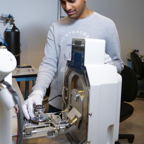 One person uses a gloved hand to interact with the machine.