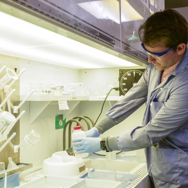 One person interacts with a bottle in the chemical lab area.