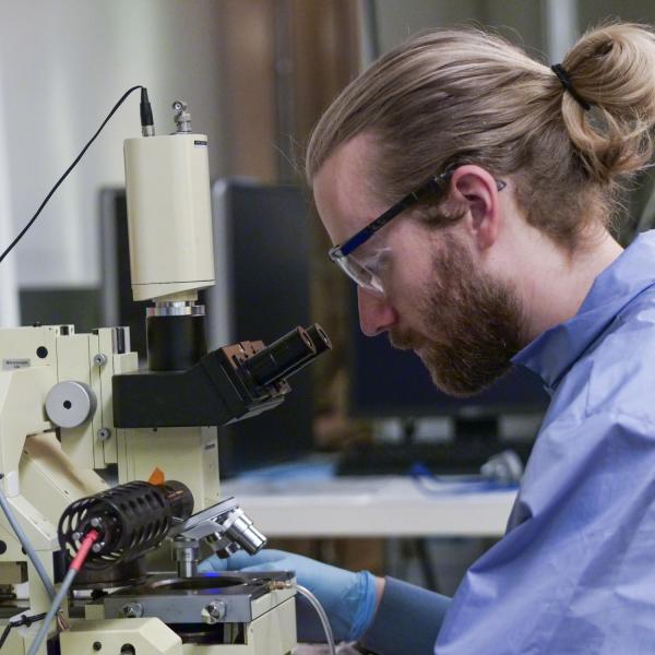 A person looks through a microscope.