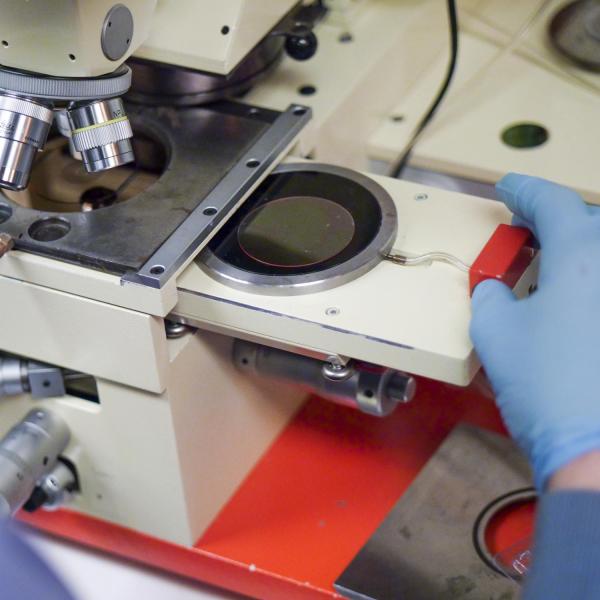 Two hands interacting with the microscope set up.