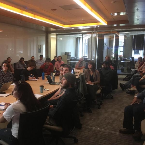 Students are sitting around a table watching a presentation