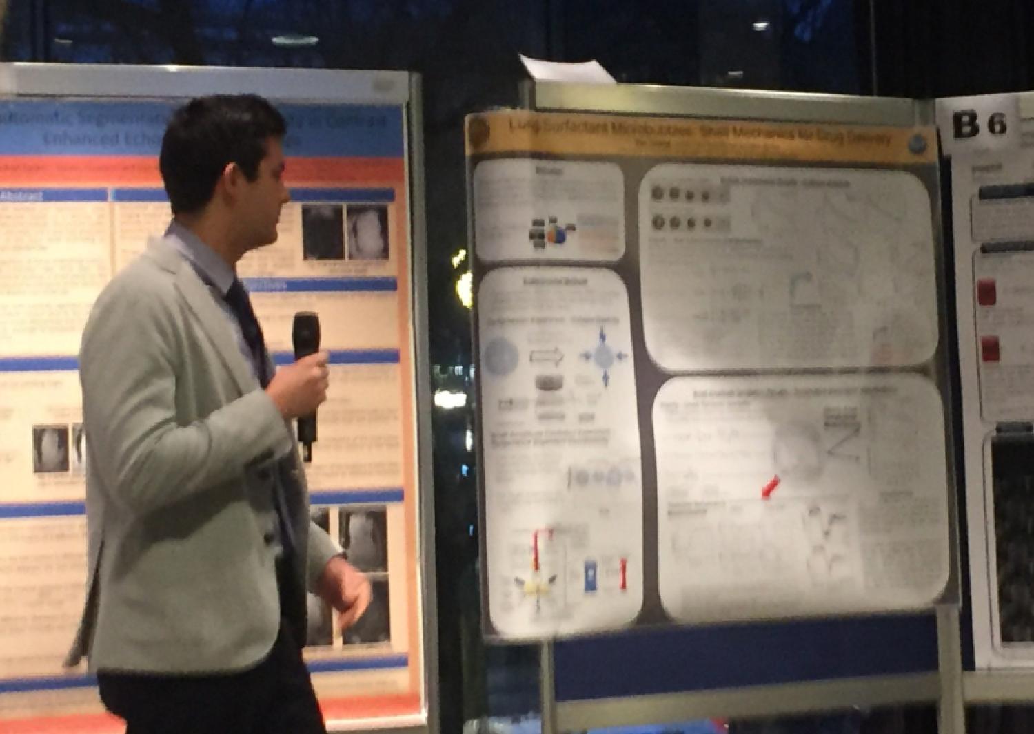 Alec Thomas standing with a microphone by some posters