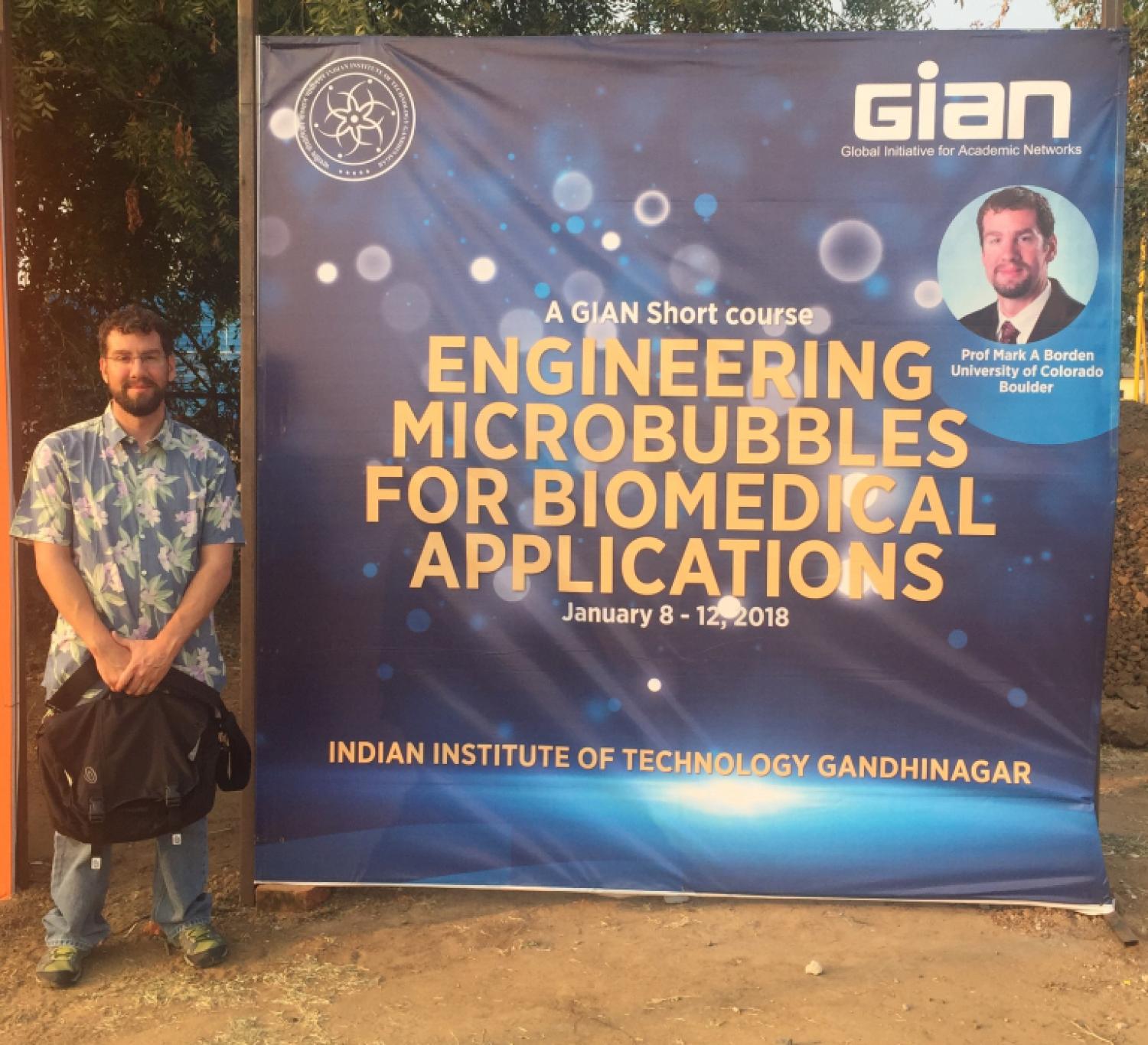 Mark Borden standing by a poster for a GIAN short course