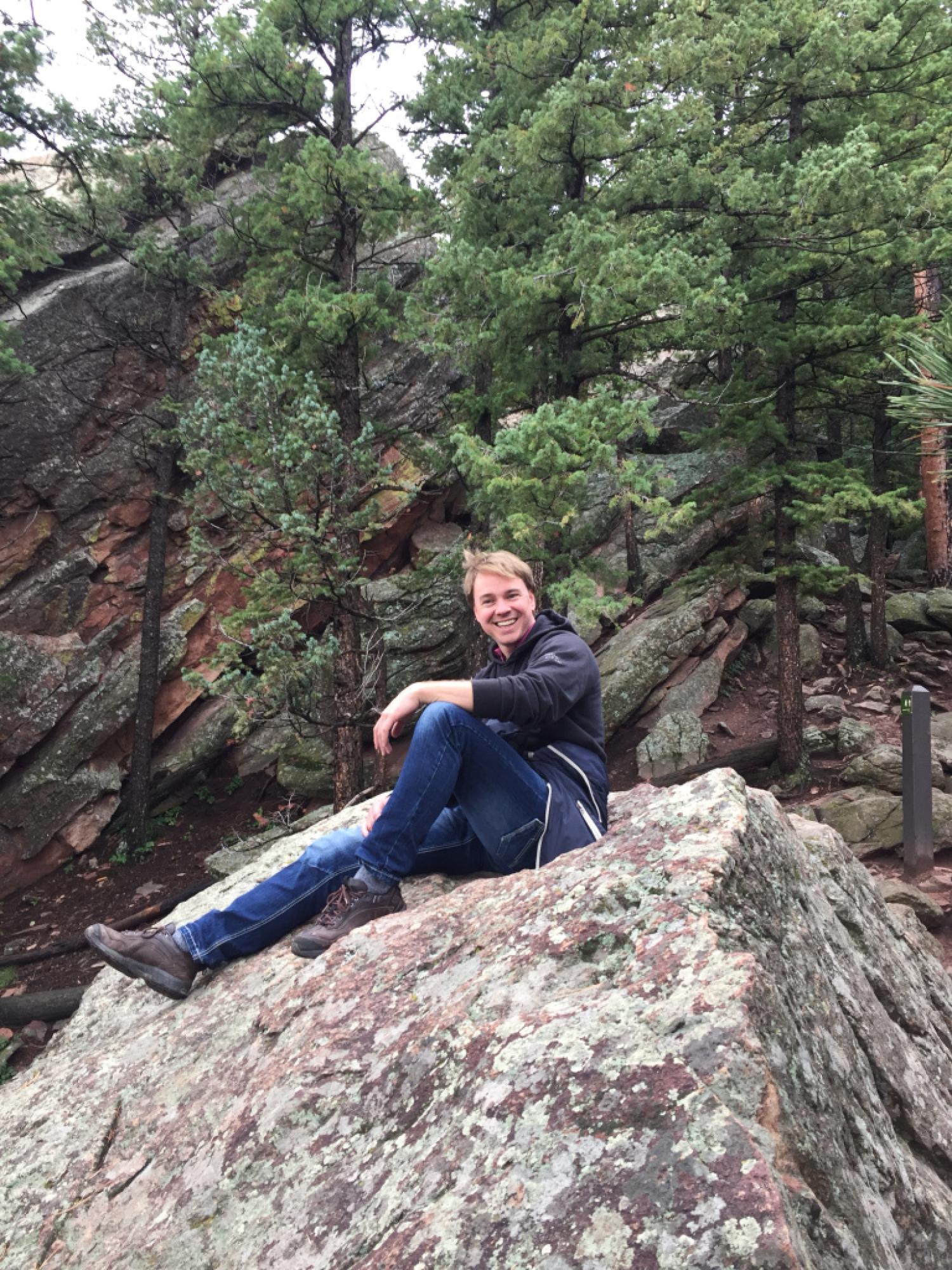 Rik Vos sitting on a rock in the woods