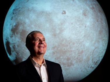 Dr. Jack Burns photo with Moon on Science on the Sphere in the background